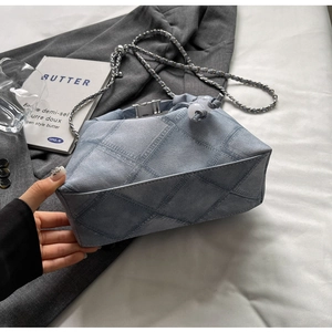 Detail of blue denim print bucket bag with silver metal buckle and chain strap