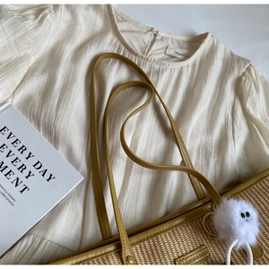Vue à plat d'un sac cabas en paille avec haut plissé crème et breloque en peluche