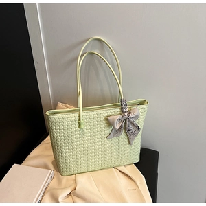 Detail of mint green woven tote bag with a decorative leaf print silk scarf on handle
