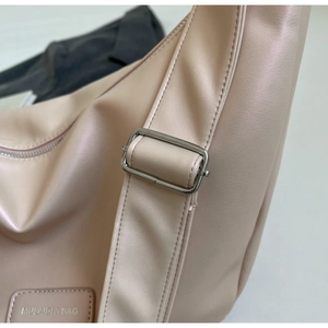 Detail of adjustable metal buckle and reinforced stitching on a light pink shoulder bag