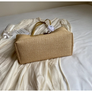 Gros plan d'un sac cabas en paille avec anses en cuir marron sur fond estival relaxant
