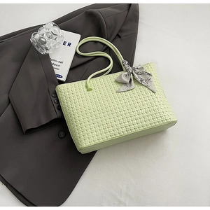 Detail of light green woven tote bag texture with floral silk scarf accessory