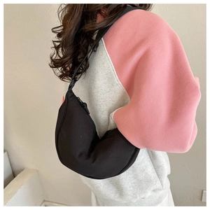 Detail of black crescent crossbody bag showing its size and drape on a model