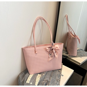 Detail of pink woven tote bag with a floral scarf accent on a denim jacket backdrop