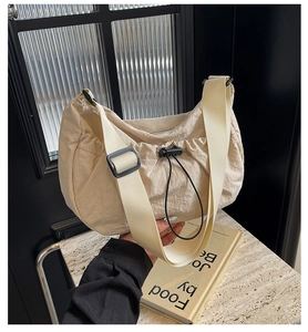 Détail du sac plissé en nylon beige avec cordon de serrage noir et bandoulière large