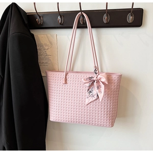 Detail of pink woven tote bag with printed silk scarf bow on a wooden hook