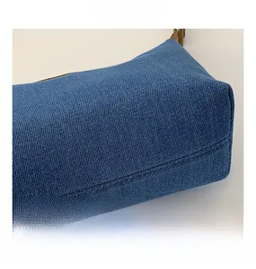 Detailed close-up of blue denim fabric texture and brown leather handle on shoulder bag