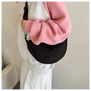 Close-up of black crescent dumpling bag with adjustable canvas strap on model side