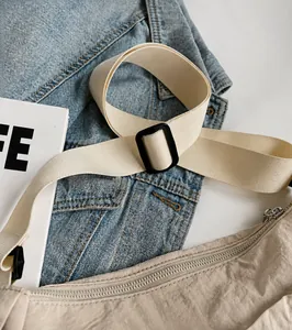 Detail of beige shoulder bag showing the wide adjustable strap and silver zipper closure