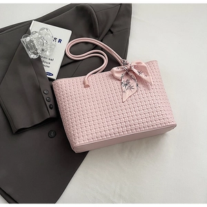 Detail of pink woven tote bag with floral silk scarf on grey blazer background