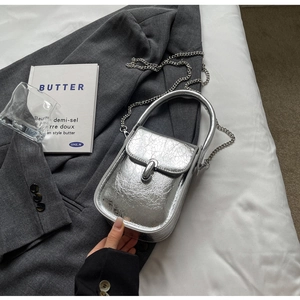Detail of silver metallic textured crossbody bag with chain strap and stylish flap closure