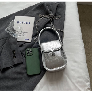 Detail of silver metallic textured mini bag with chain strap and U-shaped buckle on a blazer