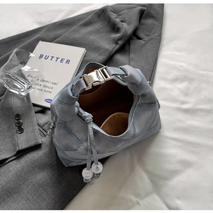 Detailed view of light blue denim bag texture featuring a metal buckle and brown lining