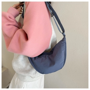 Detail showing the adjustable strap and texture of the navy blue crescent shoulder bag