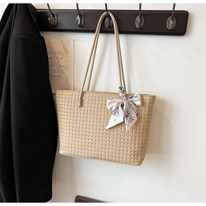 Detail of beige woven tote bag with lavender silk scarf and elegant hanging straps