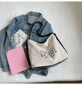 Flat lay of canvas hobo bag with contrast leather base and alphabet print detailing
