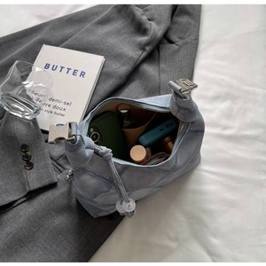 Detail view of denim dumpling bag interior holding phone and cosmetics on a blazer