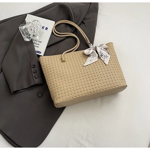 Detailed close-up of beige woven tote bag featuring a decorative printed silk scarf on handle