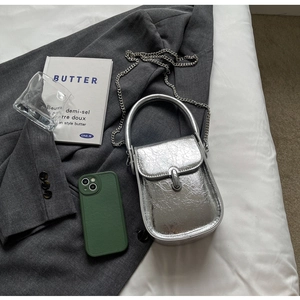 Detail of silver metallic textured mini crossbody bag with chain strap and sleek lock