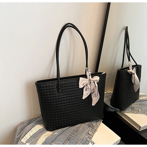Close-up of black woven tote bag with floral silk scarf and slim shoulder straps