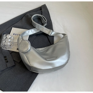 Detail of silver half-moon crossbody bag with matching round coin purse on a gray blazer