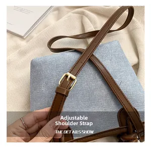 Detailed close-up of adjustable brown leather shoulder strap with gold buckle on denim bag
