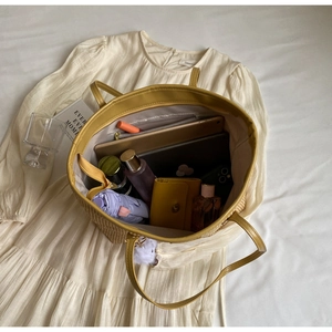 Vue de dessus d'un grand sac fourre-tout en paille rempli d'articles de voyage