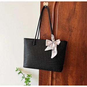 Close-up of black woven tote bag texture with elegant floral silk scarf detail
