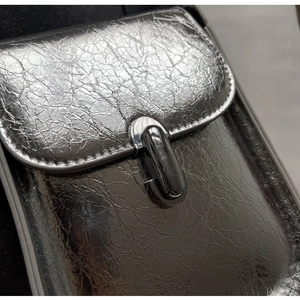 Close-up of shiny silver cracked texture leather bag with metallic lock detail