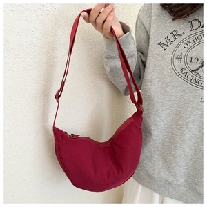 Detailed view of burgundy crescent dumpling bag with adjustable strap and metal zipper