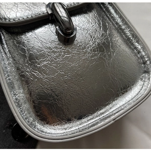Close-up of silver crinkled texture leather with dark metallic twist lock on handbag