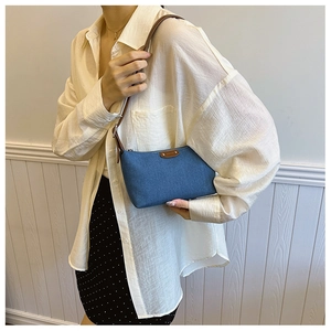 Close-up of retro denim blue hobo bag with brown leather accents on a model outfit