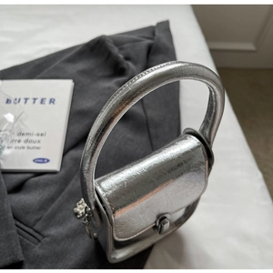 Detail of silver pleated leather mini bag with metallic handle and chain detail