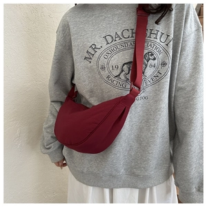 Detail of burgundy crescent dumpling bag with pleated fabric and adjustable strap
