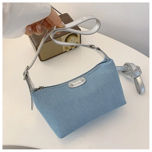 Detailed close-up of vintage denim shoulder bag with silver strap and metallic brand plate