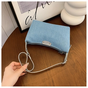 Detail of vintage blue denim hobo bag with silver zipper and leather buckle strap