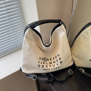 Chic beige herringbone canvas tote bag with black leather handles and printed text