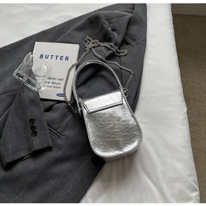 Macro shot of silver metallic crinkled texture handbag with elegant chain strap and handle