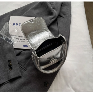 Detailed top view of silver textured leather bag with metallic clasp and black interior