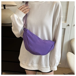 Close-up of a purple crescent dumpling bag made of soft fabric with an adjustable strap