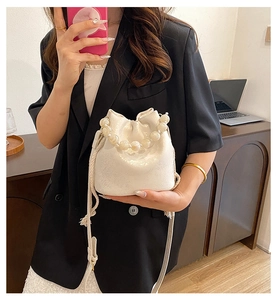 Detail of white pleated bucket bag with pearl handle and drawstring closure for women