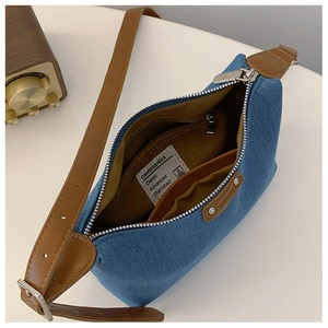 Internal view of blue denim crossbody bag featuring brown faux leather trim and lining