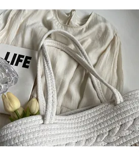 Détail du sac cabas tissé blanc montrant la texture en maille et l'anse robuste