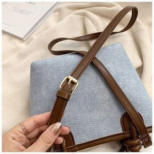 Detailed shot of adjustable leather strap and golden buckle on denim bucket bag