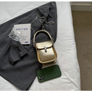Top-down view of golden mini handbag with metallic texture and silver chain strap on a blazer