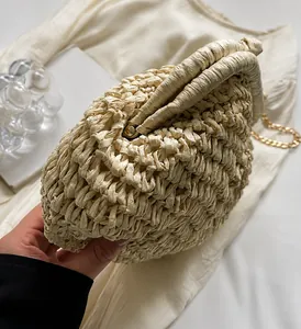 Détail du sac en paille tressée beige montrant la texture et la bandoulière dorée