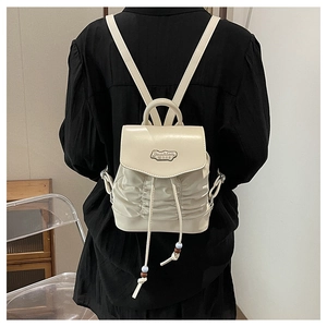 Detail of the pleated texture and drawstring flap on this cream white mini backpack