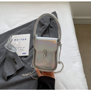 Detailed view of iridescent small square bag with silver chain strap on grey blazer