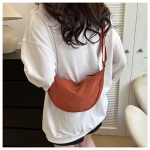 Detailed back view of a caramel orange half-moon crossbody bag with adjustable strap