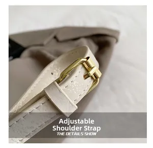 Detailed macro view of an adjustable cream shoulder strap with premium gold metal buckle